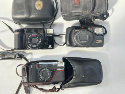 trois appareils photo et un étui posés sur une table blanche