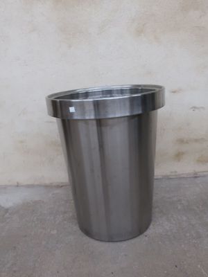a metal trash can sitting in front of a wall