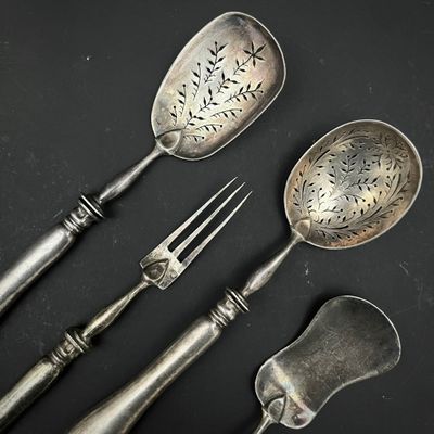 trois cuillères et une fourchette en argent sur une surface noire