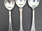 three silver spoons and two silver spoons on a black surface