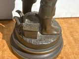 une statue en bronze représentant un homme avec un panier posé sur une table
