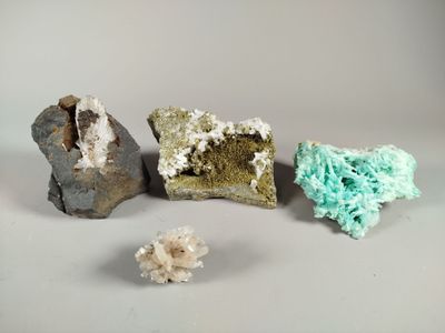 three different colored rocks and a piece of rock on a white surface