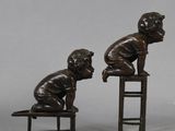pair of bronze figurines of a boy and a girl sitting on a chair
