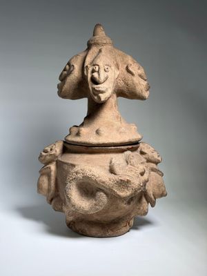 une image représentant un vase en argile surmonté d'un visage