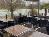 des tables et des chaises sur une terrasse en bois donnant sur un plan d'eau