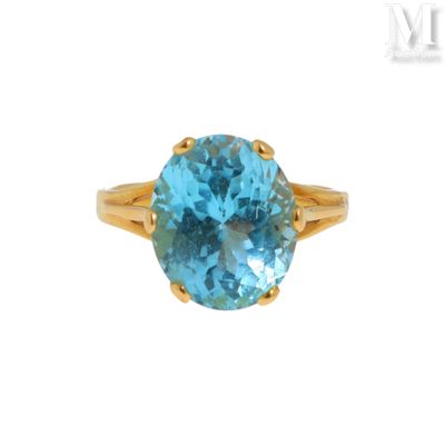 Gros plan sur une bague en or ornée d'une topaze bleue
