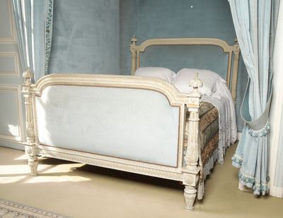 a bed with a white frame in a room with blue walls