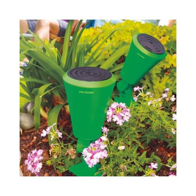 two green garden hoses sitting in the middle of a flower bed
