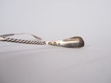 silver spoon with a long handle sitting on a white surface