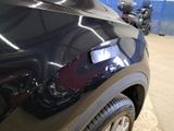 a close up of a car ' s rear end with a motorcycle in the background