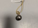 a close up of a necklace with a black pearl hanging from it
