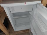 a small white refrigerator with its door open in the kitchen