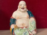 une statue représentant un Bouddha souriant, assis sur une table