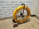 a yellow hose on a cart in front of a wall