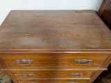 a wooden chest of drawers next to a bed