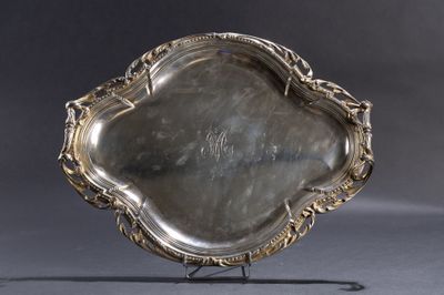 un plat ancien en argent, orné d'un motif décoratif, posé sur un socle