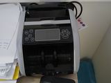 une imprimante posée sur un bureau, à côté d'une pile de papiers