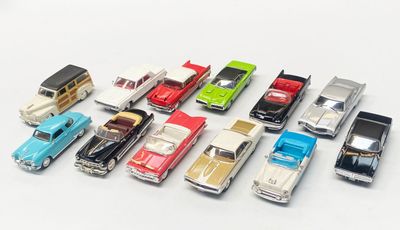 several toy cars are lined up in a row on a white surface