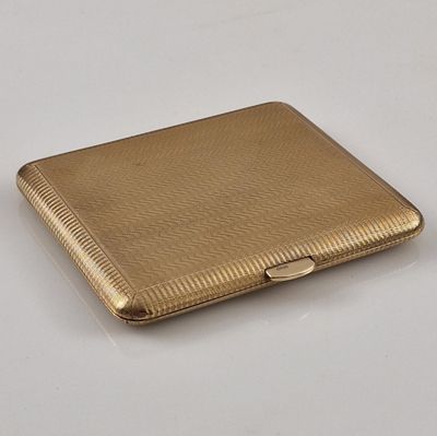 an image of a gold cigarette case sitting on top of a white table
