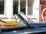 a man sitting in a black convertible car outside of a building