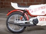 a red and white motorcycle parked in front of a brick wall