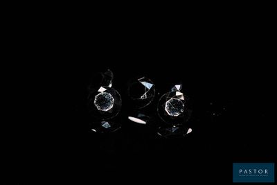 two pieces of diamond on a black surface with a black background
