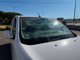 a white car with a broken windshield on the side of the road