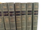 several old books are lined up in a row on a white surface