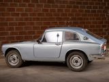 a silver car that is parked in front of a brick wall