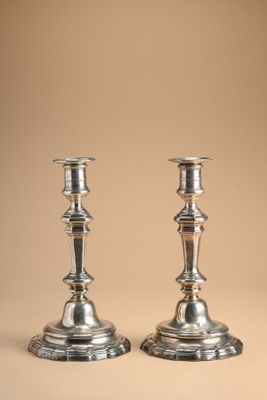 pair of silver candlesticks on a beige background