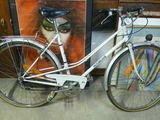 un vélo blanc garé à côté d'un tableau accroché au mur