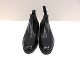 a pair of black leather chelsea boots on a white surface