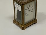 une petite horloge en laiton avec des chiffres romains sur le cadran