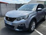 La voiture grise est garée sur le parking à côté de l'immeuble.