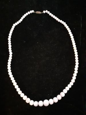 a white pearl necklace with a gold clasp on a black background