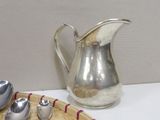 a plate with spoons and a silver pitcher on it