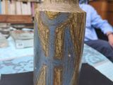 a vase sitting on a table with a man in the background