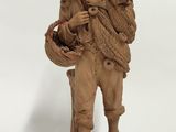figurine représentant un homme portant un panier sur le dos