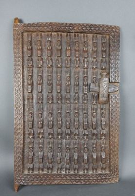une vieille porte en bois ornée de sculptures sur une surface grise