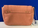 an orange purse sitting on top of a white table next to a blue wall