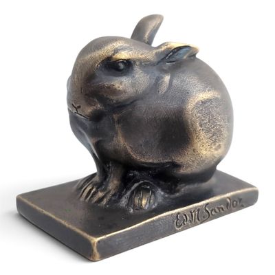 une sculpture en bronze représentant un lapin assis sur un socle