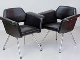 pair of black leather chairs with chrome legs on a white floor