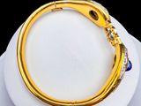gold plated bracelet with blue and white stones on a white plate