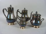 three pieces of silver tea and coffee set on a white surface