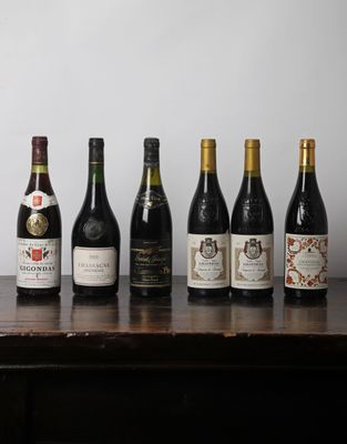 Des bouteilles de vin sont alignées sur une table devant un mur blanc.