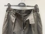 grey pants hanging on a hanger on a white wall