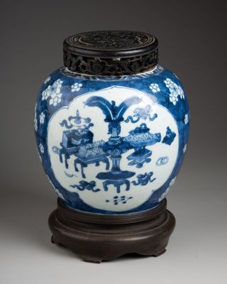 blue and white vase with a wooden stand on a gray surface