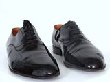 pair of black leather shoes on a white surface with a white background