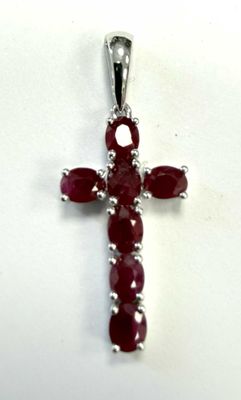 un gros plan d'une croix ornée d'une pierre rouge