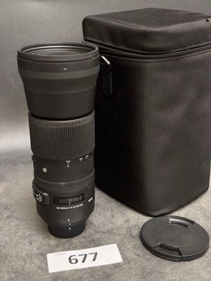un objectif d'appareil photo posé à côté d'un étui, par terre